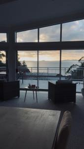 a living room with a table and a large window at Doubtless Bay Retreat in Coopers Beach