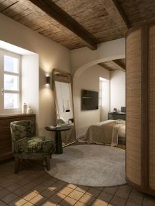 a bedroom with a bed and a mirror and a chair at BORGO MONCHIERO HERITAGE by Atmosphere in Monchiero