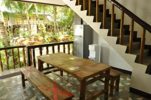 a wooden table and bench on a balcony with a staircase at Paseo Verde Beach Resort in Laiya