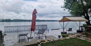 a patio with chairs and an umbrella next to a lake at Vikendica Emily in Kovin