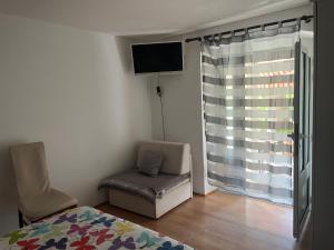 ein Schlafzimmer mit einem Bett, einem Stuhl und einem Fenster in der Unterkunft Apartment and Room Surdić in Valun