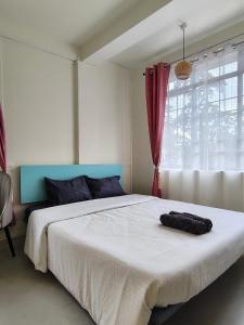 a bedroom with a large white bed and a window at Urbanest B&B in Shillong