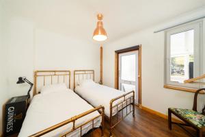 two beds in a room with a window and a chair at Meadowview in Lochearnhead