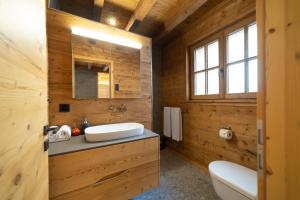 a wooden bathroom with a sink and a toilet at Chalet Selun - Luxury & Bergblick in Wildhaus +17 photos