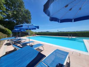 a swimming pool with two blue chairs and umbrellas at Agriturismo Fontesomma in Apecchio