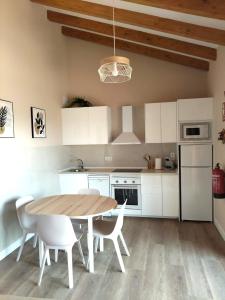 a kitchen with a wooden table and white cabinets at Apartamentos Turísticos El Collau in La Robellada de Onis