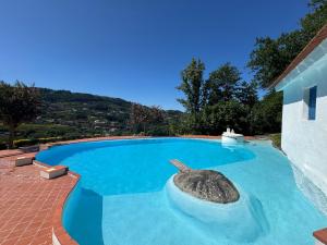 a swimming pool with a rock in the middle at Casa da Agrela in Ponte da Barca