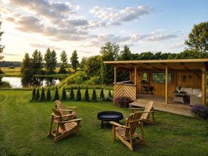 eine Hütte mit Stühlen und einem Grill im Gras in der Unterkunft Brīvdienu māja Straumēni in Pāle