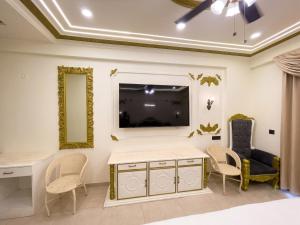 a living room with a tv and a desk and chairs at Hotel Om Sai Villa Gomti Nagar, Lucknow in Lucknow
