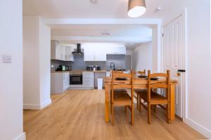 a kitchen and dining room with a wooden table and chairs at New 3 Bedroom Apartment Next to Station in Chepstow