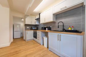 a kitchen with white cabinets and a sink at New 3 Bedroom Apartment Next to Station in Chepstow +11 photos
