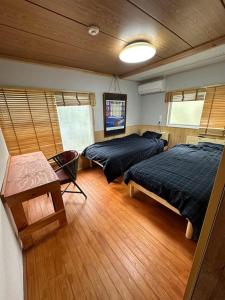 a bedroom with two beds and a wooden floor at Kujukuri SHICHIFUKU in Hasunuma