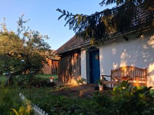 a wooden bench sitting outside of a white house at Pacsirta Porta in Nemesnép +17 photos
