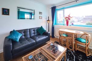 a living room with a leather couch and a table at Host & Stay - Beachcomber Cottage Apartment in Morecambe