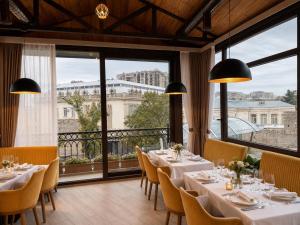 ein Restaurant mit Tischen und Stühlen und großen Fenstern in der Unterkunft Seven Beautiess Hotel in Baku