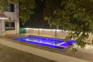 a swimming pool with blue lighting in a backyard at night at Coastal Gateway Resort in Revadanda +4 photos