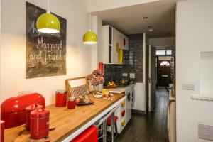ロンドンにあるDownhills Homeのキッチン(木製カウンター、赤い椅子付)