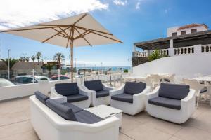 a patio with lounge chairs and an umbrella at Ona el Marqués in Puerto de Santiago