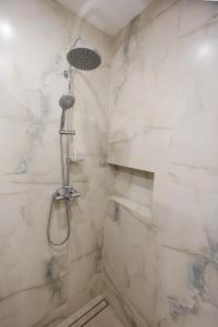 a bathroom with a shower with white marble walls at Przystań Hartowiec in Ostaszewo