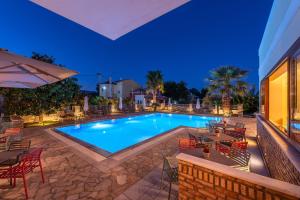 a swimming pool with tables and chairs and a patio at Harmony Hotel Apartments in Selianitika
