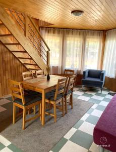 a dining room with a table and chairs and a staircase at Kotedžiukai Šventojoje in Šventoji +29 photos