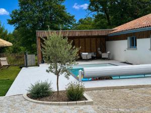 a swimming pool next to a house with a tree at Quilleret in Haut-Mauco