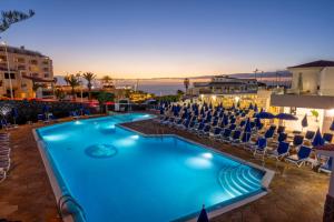 a swimming pool with chairs and the ocean at dusk at Ona el Marqués in Puerto de Santiago