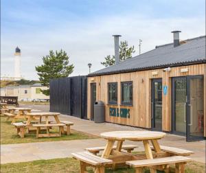 a group of picnic tables in front of a building at Sunset View - with view of the lighthouse and a shower and bath in Lossiemouth