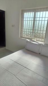 a bedroom with a white bed with a large window at Sai Residency in Pallineriyanur
