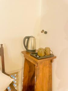 a table with a tea kettle and mugs on it at Ayubowan Home in Galle
