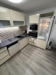 a large kitchen with white cabinets and a refrigerator at Apartmán 1, Heydukovka in Písek