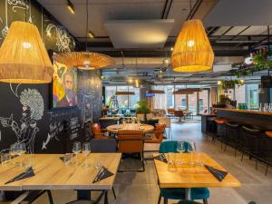 a restaurant with wooden tables and chairs and lights at ibis Styles Amiens Centre in Amiens