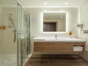a bathroom with a sink and a shower with a mirror at ibis Styles Kraków East in Krakow