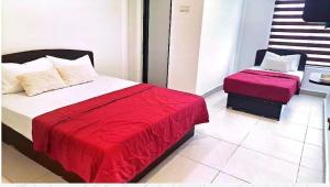 a bedroom with two beds with red sheets and a chair at Hotel Lii View in Mersing +6 photos