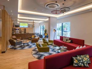 a waiting room with red couches and chairs at ibis Styles Magdeburg in Magdeburg