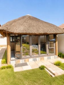 a pavilion with a thatched roof and grass at Azania Bed & Breakfast in Meyerton