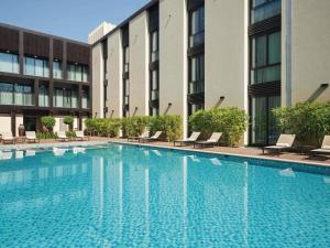 a swimming pool in front of a building at Mövenpick Hotel Tahlia Jeddah in Jeddah