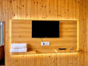 a flat screen tv on a wooden wall at The Amber Retreat - Best Property In Mussoorie #Luxury Rooms #Balcony #Parking #Budget Friendly #Mountain View #Restaurant #Couple Friendly in Mussoorie +17 photos