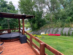 a wooden deck with a hot tub on the grass at Relax nad Narwią u Oli Pawła in Chmielewo