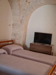 a room with two beds and a tv on a dresser at IL TRULLO GENTILE ALBEROBELLO in Alberobello +9 photos