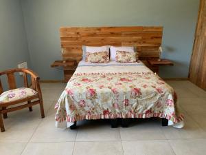 a bedroom with a bed with a floral bedspread at Viejo Boldo hotel y cabañas in Curepto +2 photos