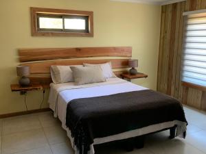 a bedroom with a large bed with a wooden headboard at Viejo Boldo hotel y cabañas in Curepto