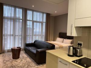 a living room with a couch and a bed and a kitchen at Urban Awe Apartment- iTowers 18th Floor in Gaborone