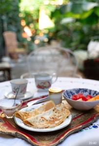 a table with a plate of food and a bowl of fruit at Chambre d'hôte Maison Magda in Beaucaire