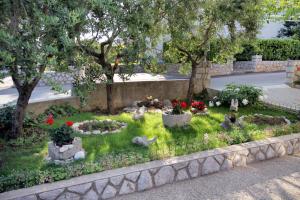 a garden with flowers and statues in the grass at Rooms with a parking space Krk - 5371 in Krk