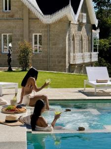 two women sitting next to a swimming pool with food at Villa Boutique 1880-Romantic Historic Boutique Hotel with Outdoor Jacuzzi in San Salvador