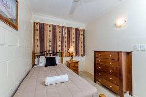 a bedroom with a bed and a dresser and a dresser at Como Apartments Gladstone in Gladstone