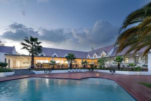 a swimming pool in front of a building with palm trees at Protea Hotel by Marriott Chingola in Chingola