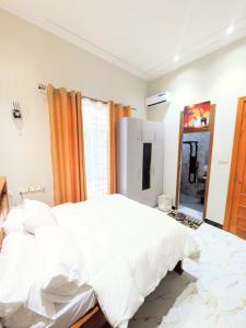 a bedroom with a large white bed and a mirror at R&E Apartments in Dodoma