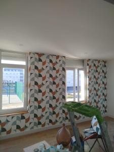 a room with two windows and a wall covered in geometric wallpaper at Le Cocon de Mollien avec Cour in Calais